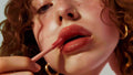 Close-up of a woman applying lip gloss, promoting smooth and hydrated lips with Vanilla Body Butter.