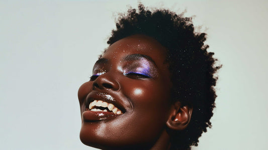 Smiling woman with glowing skin and purple eyeshadow wearing the Lip Lover Set makeup products.