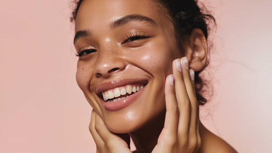 Close-up of a smiling woman with clear glowing skin gently touching her face using Jasmine Bundle products