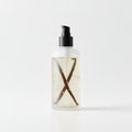 Clear bottle of Vanilla Body Oil with pump dispenser and visible vanilla pods inside on white background